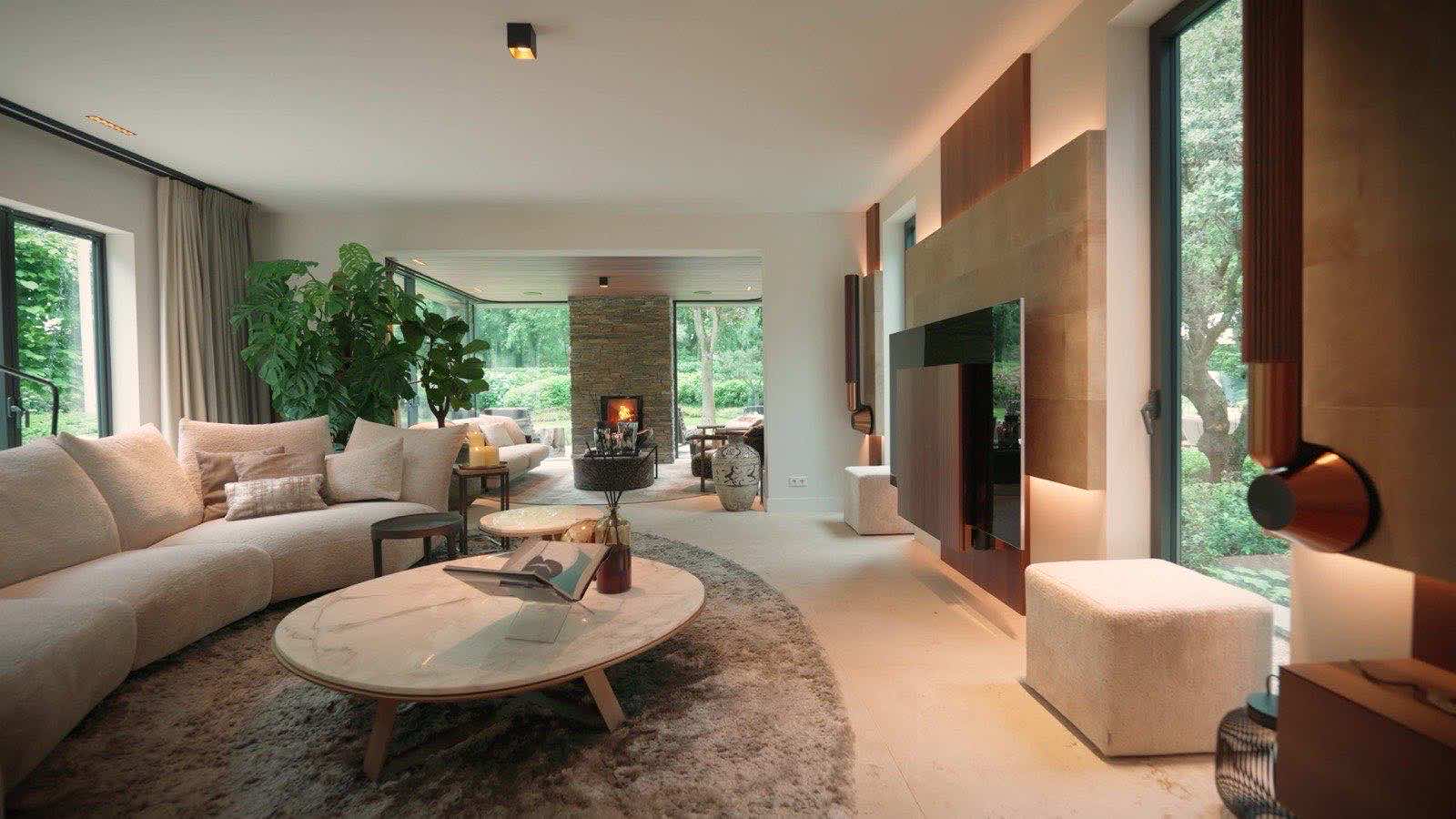 An open-plan living room with wooden accent walls, a marble table and glass doors onto the garden.