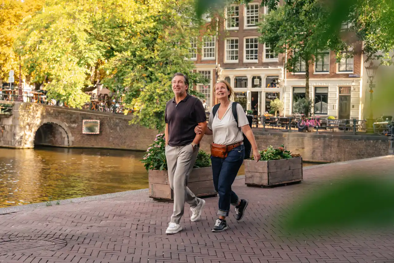 A couple walking along an Amsterdam canal in autumn