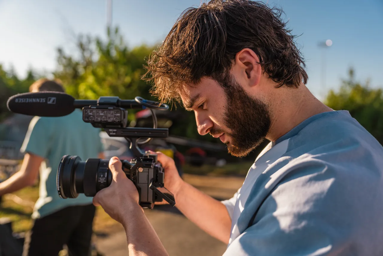 A camera operator filming with a shoulder-mounted cinema camera