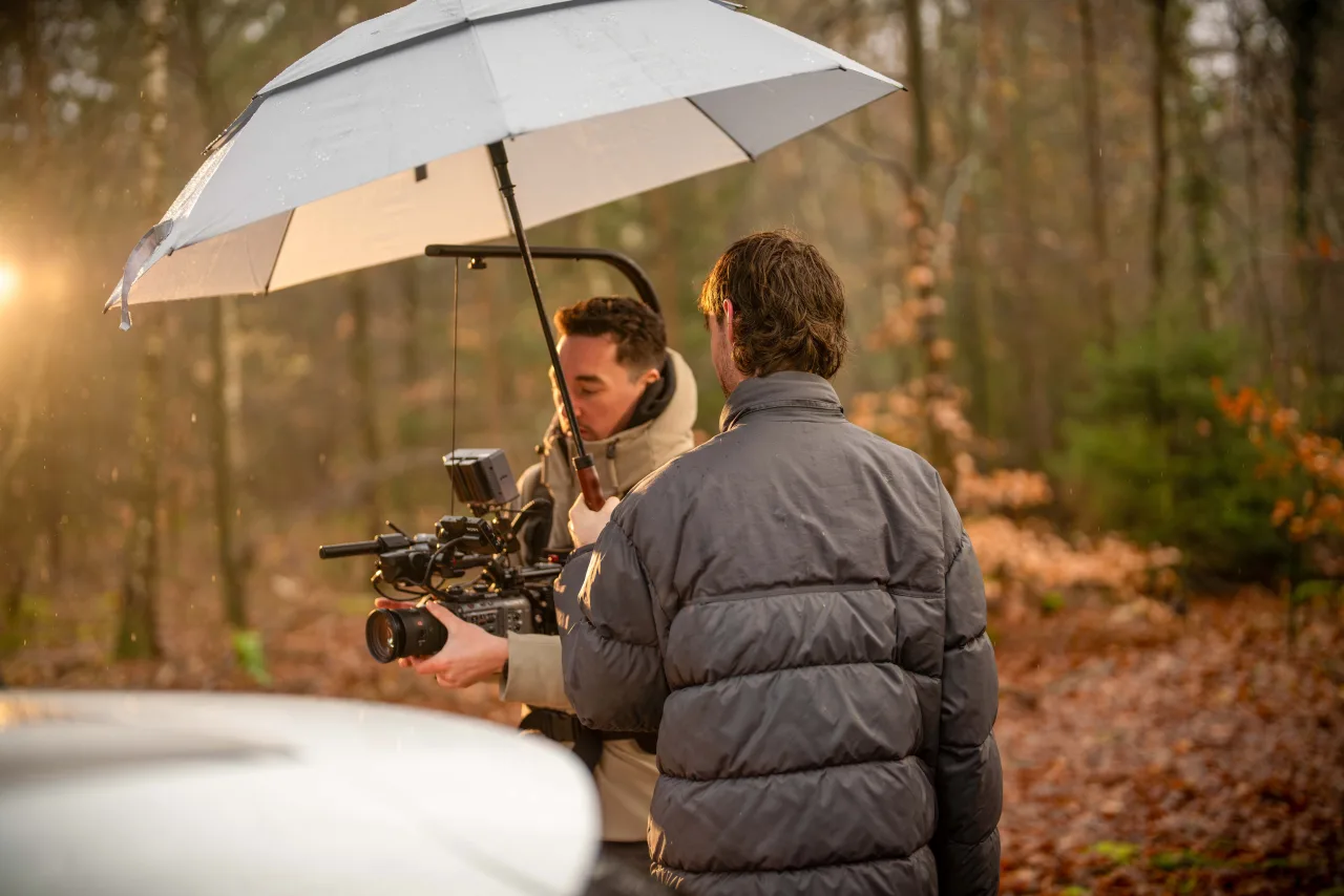 A crew filming in woodland under a large diffusion umbrella