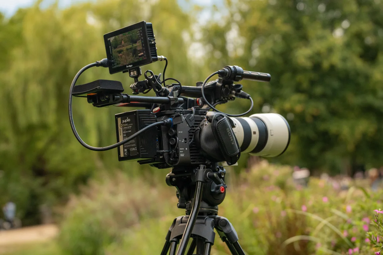 A cinema camera on a tripod with a long lens