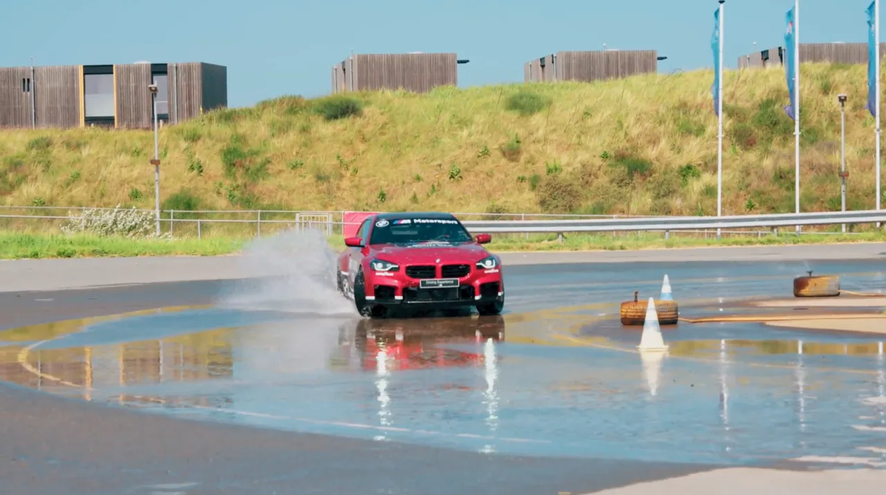 A car on a wet handling track, throwing spray