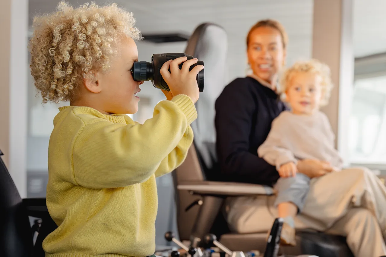 A child looking through binoculars aboard a ferry