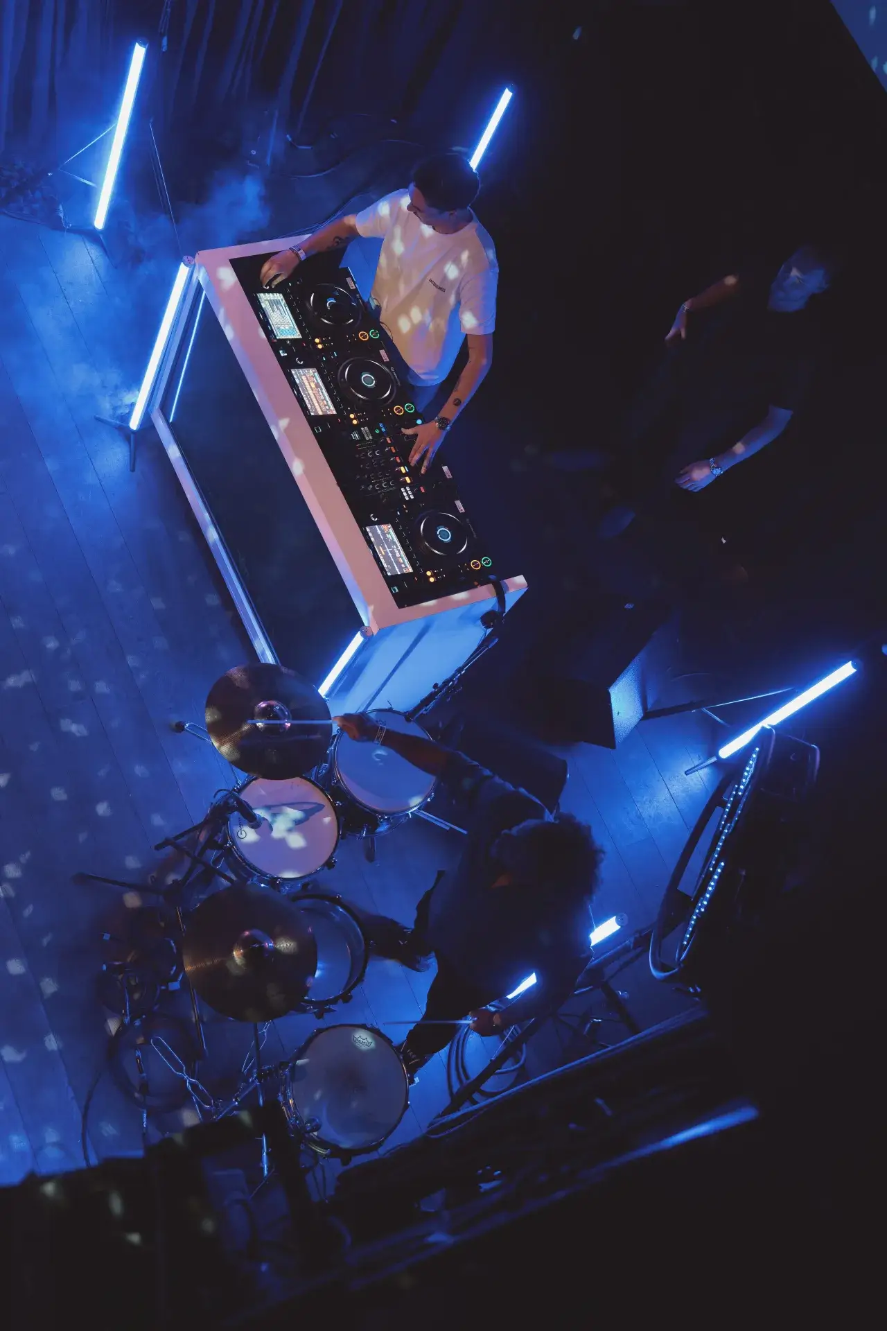 A drum kit and production gear in a blue-lit studio